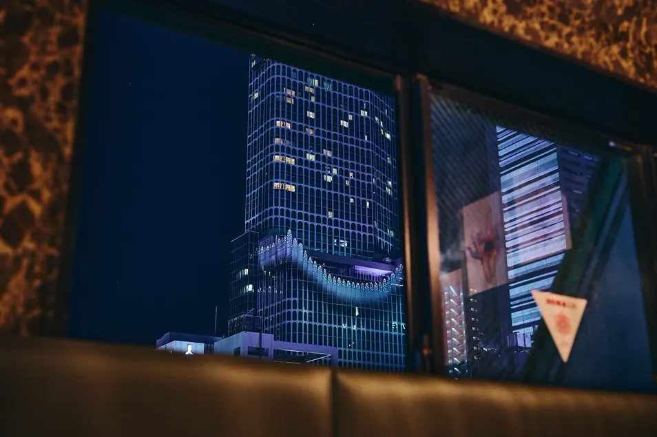 客席の窓から見える新宿・歌舞伎町の高層ビルの夜景
